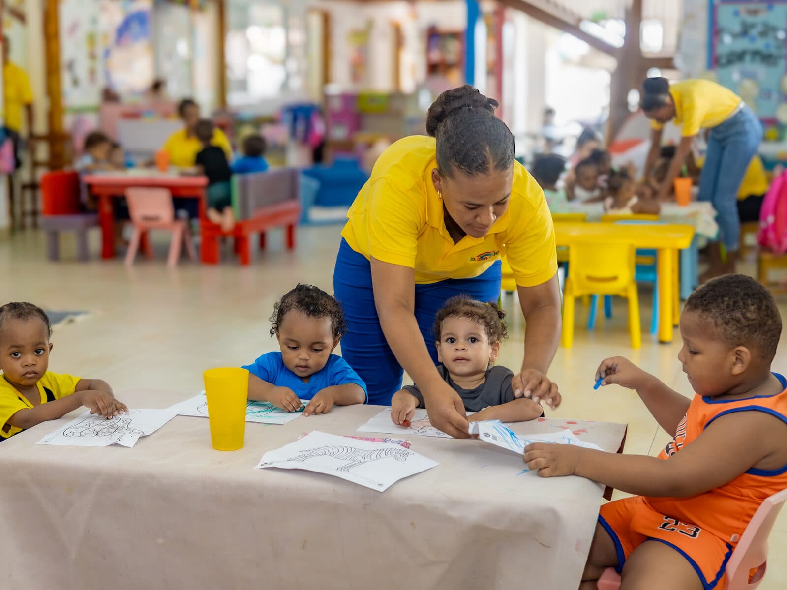 A teacher and children colouring together at a craft table