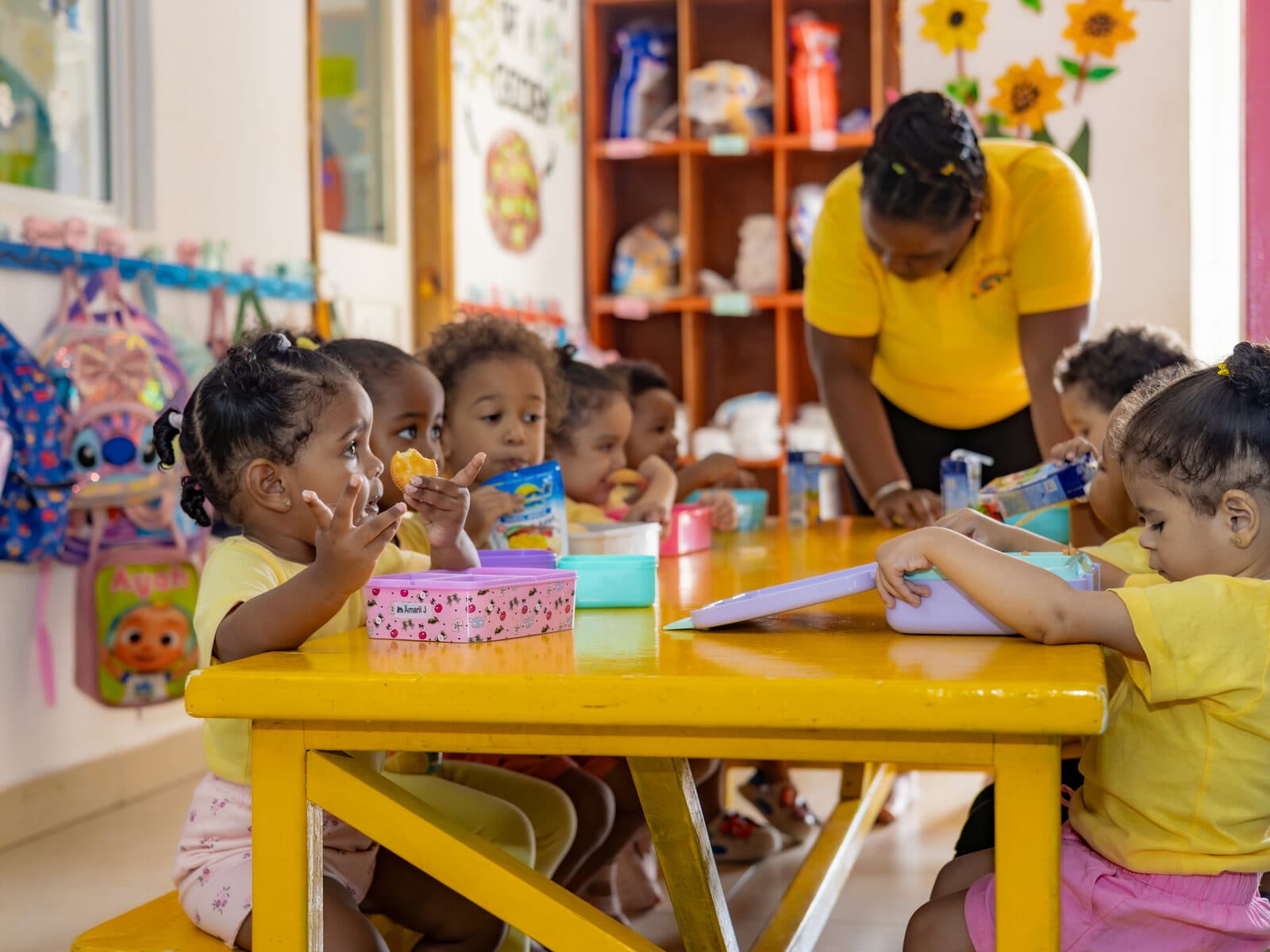 A teacher helping children with a craft activity in a bright classroom corner