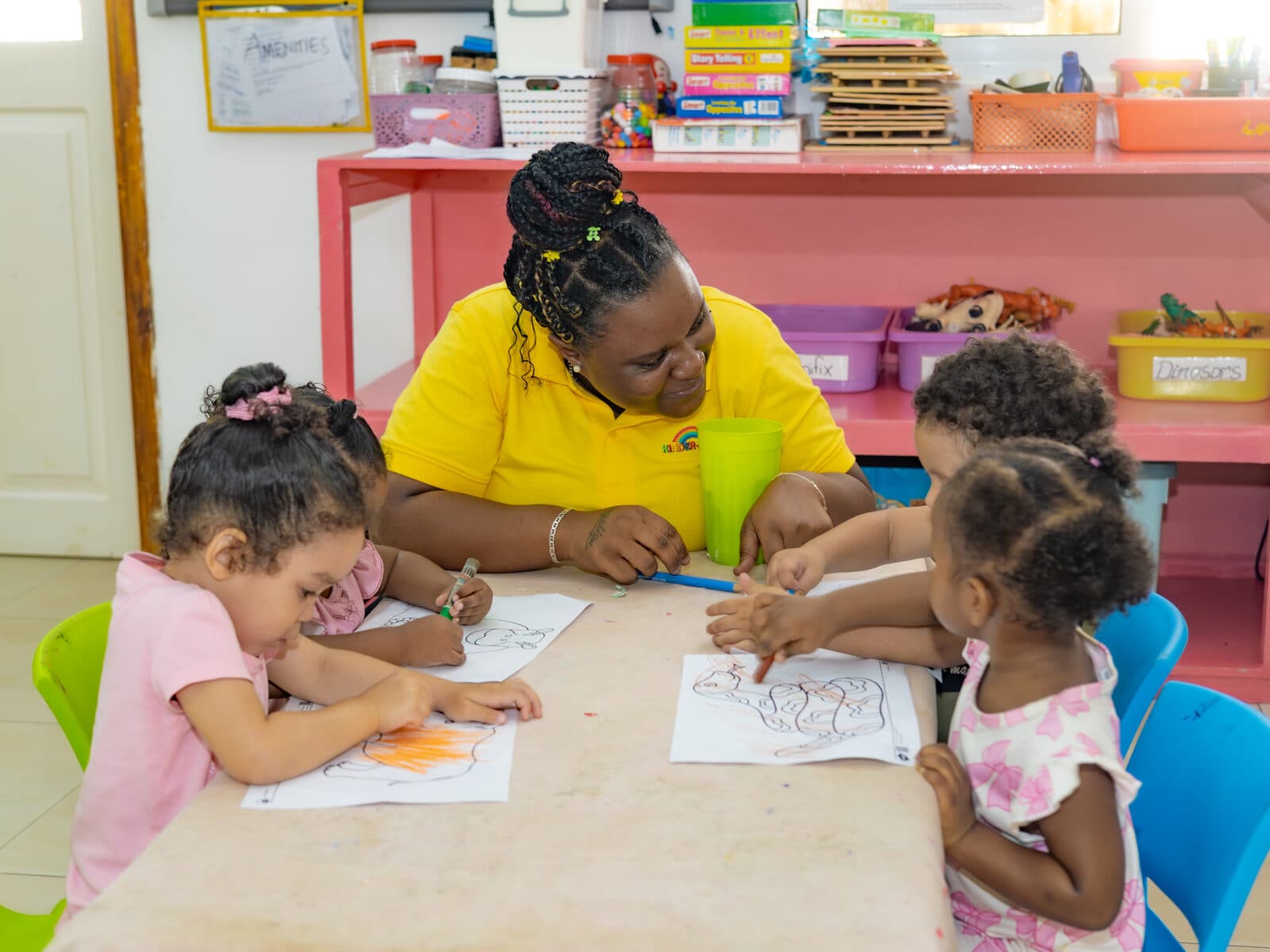 A teacher and children working together at a classroom craft table