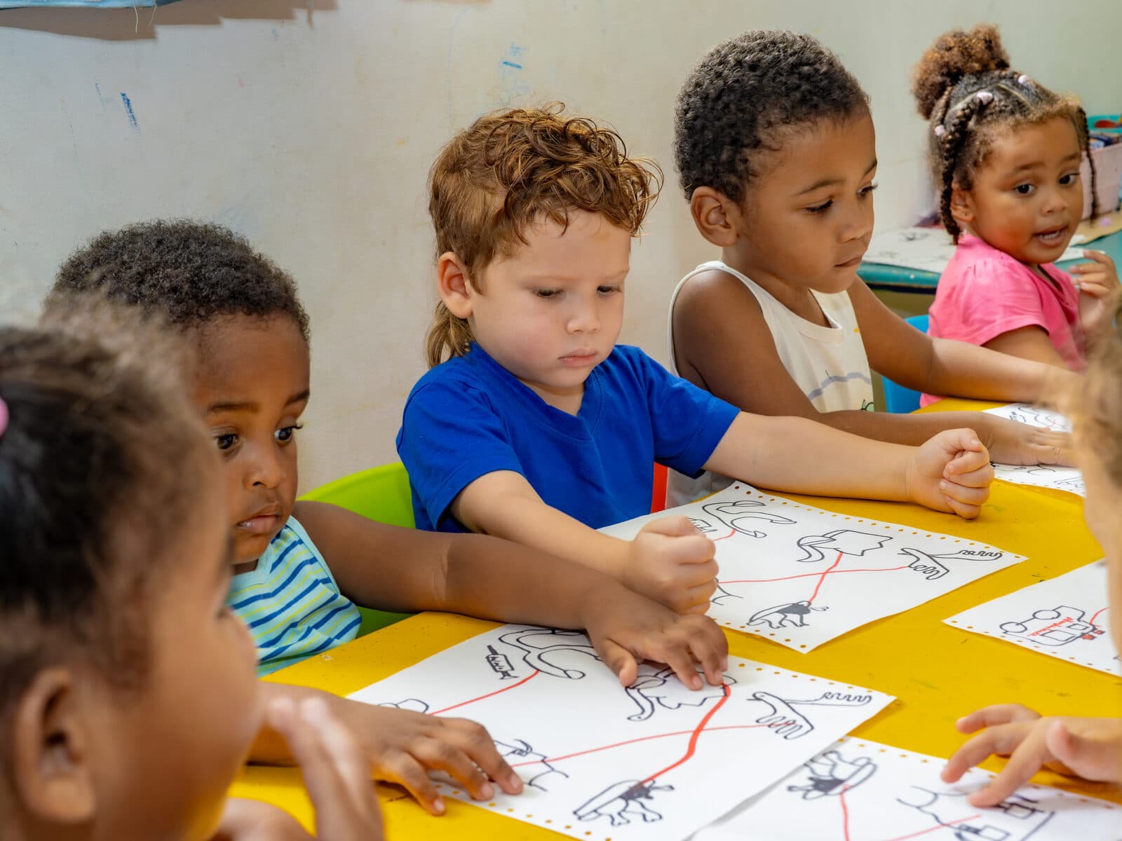 A group of children drawing together at a colourful craft table