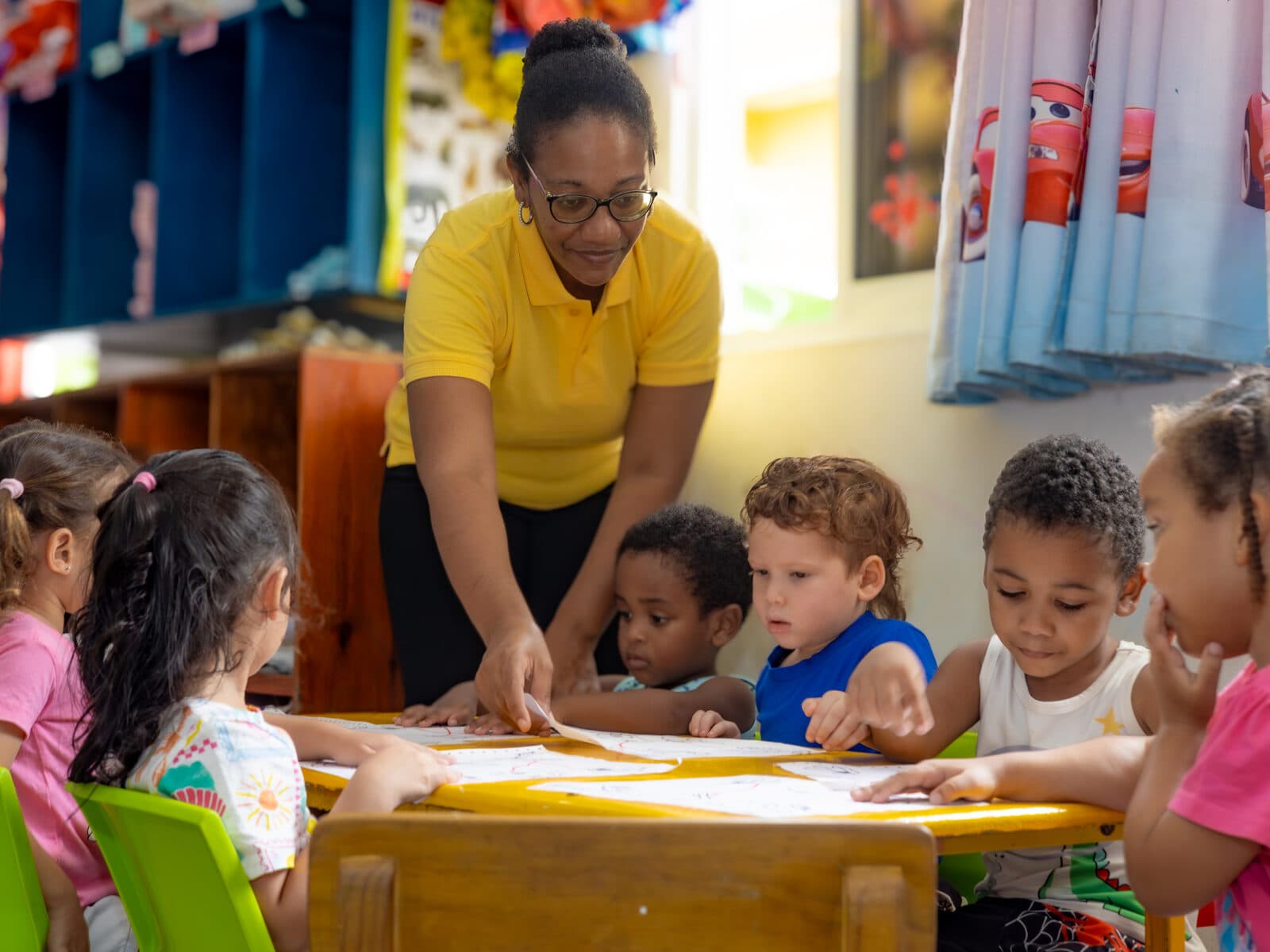 A group of children colouring together at a yellow craft table