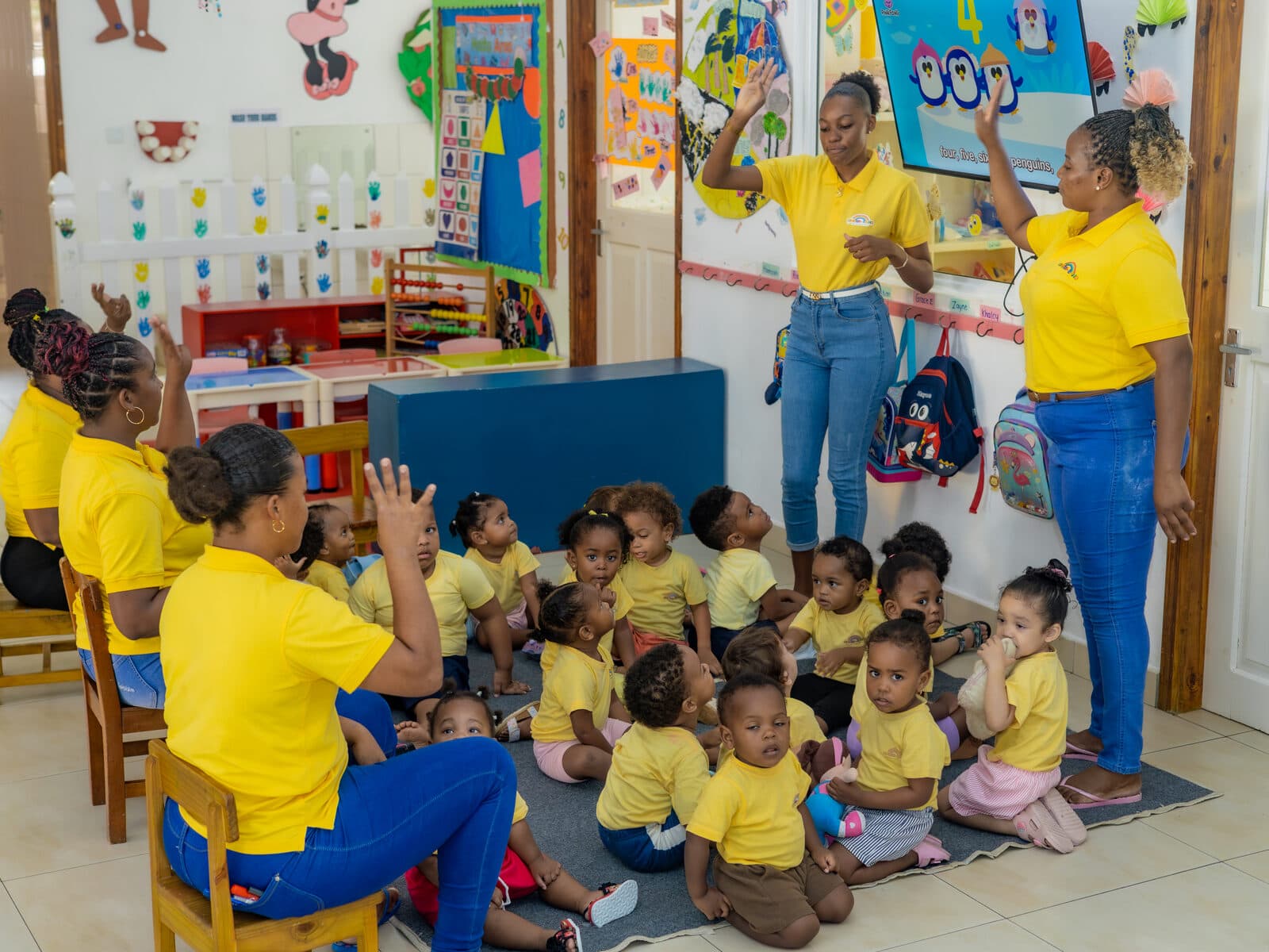 A teacher leading children in a circle time song with hand movements