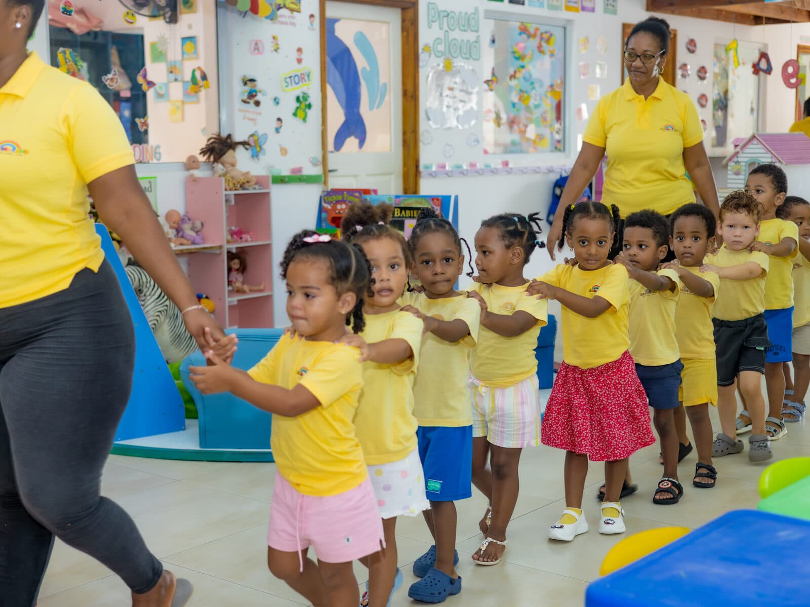 A teacher walking with children lined up together indoors