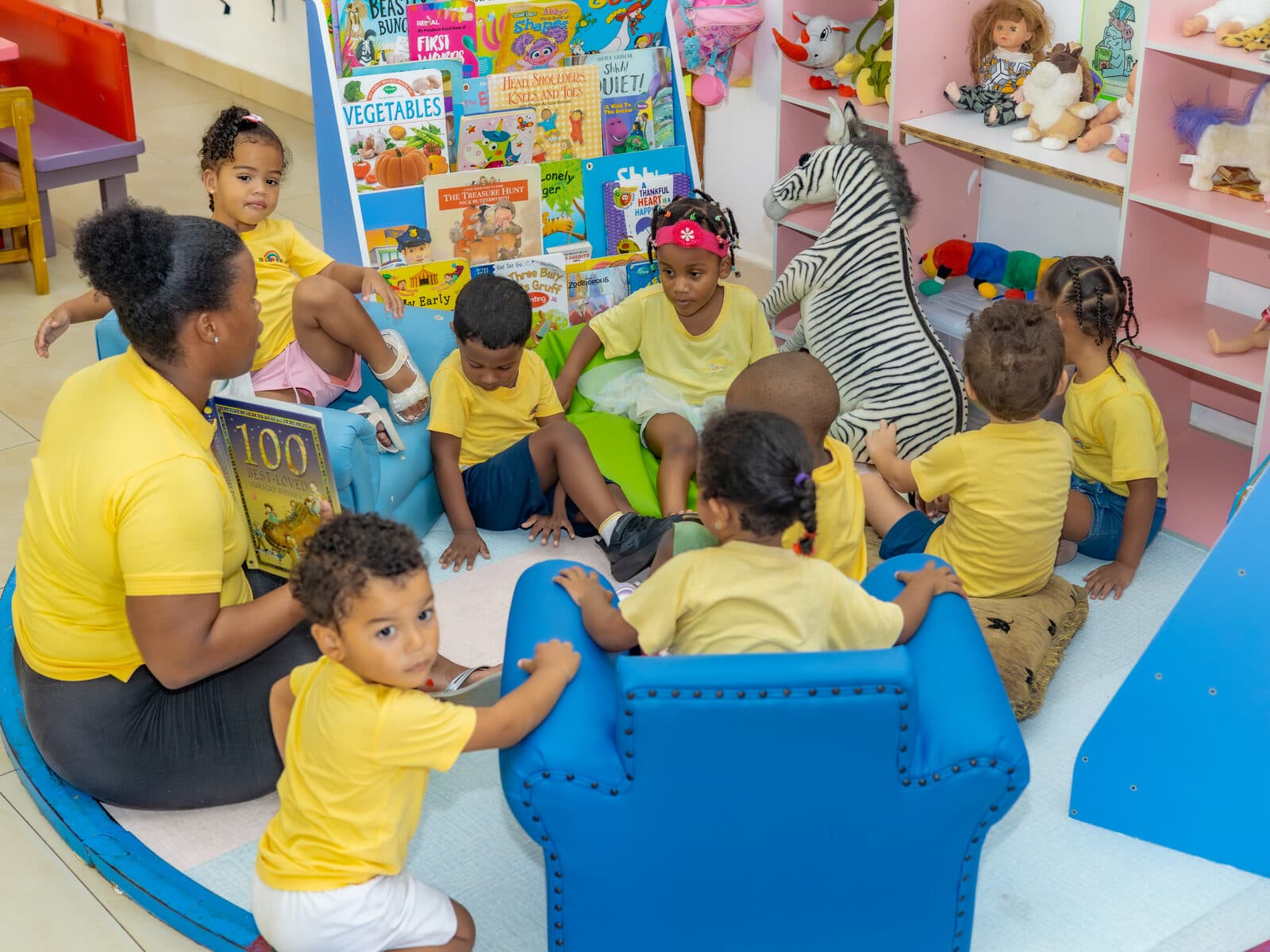 A teacher reading picture books with children on a cushioned reading nook bench