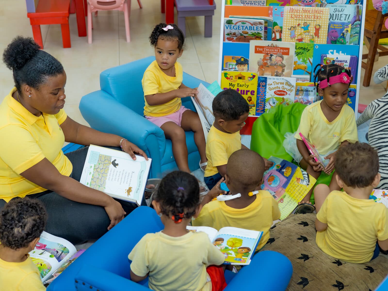 A teacher reading with children gathered on a cushioned bench