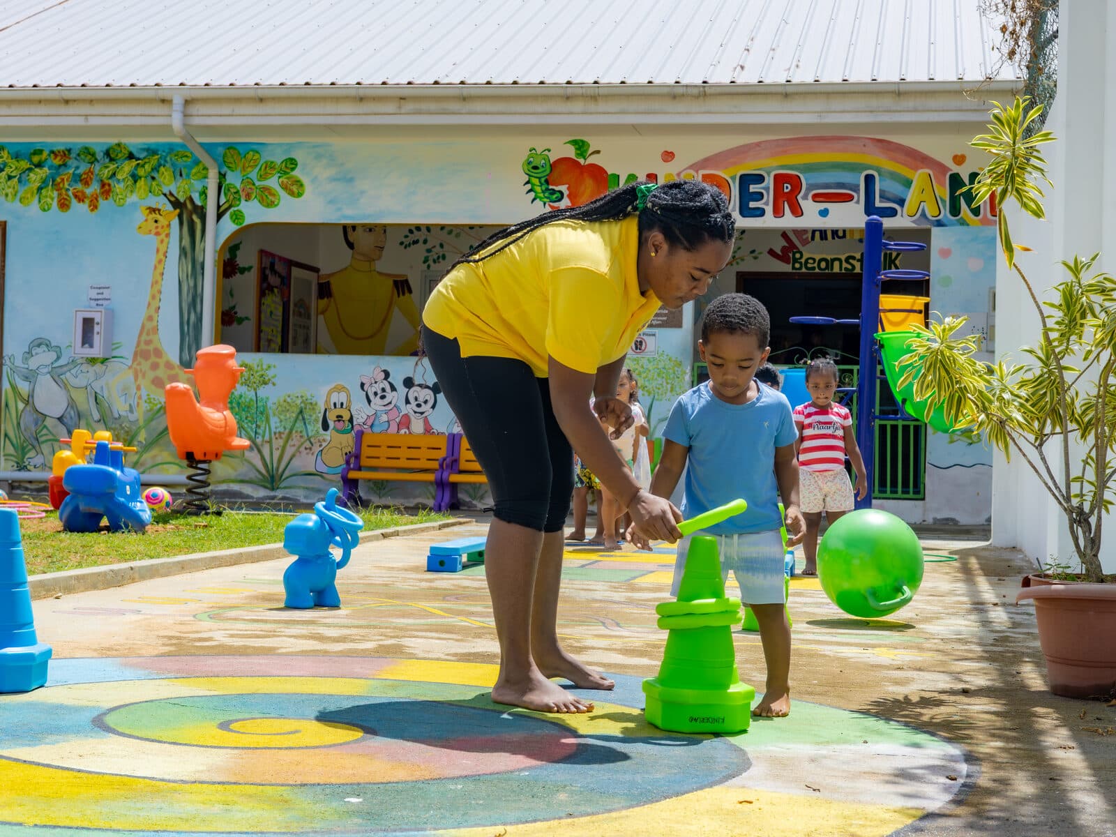 A teacher and children playing with a ball on the outdoor activity court