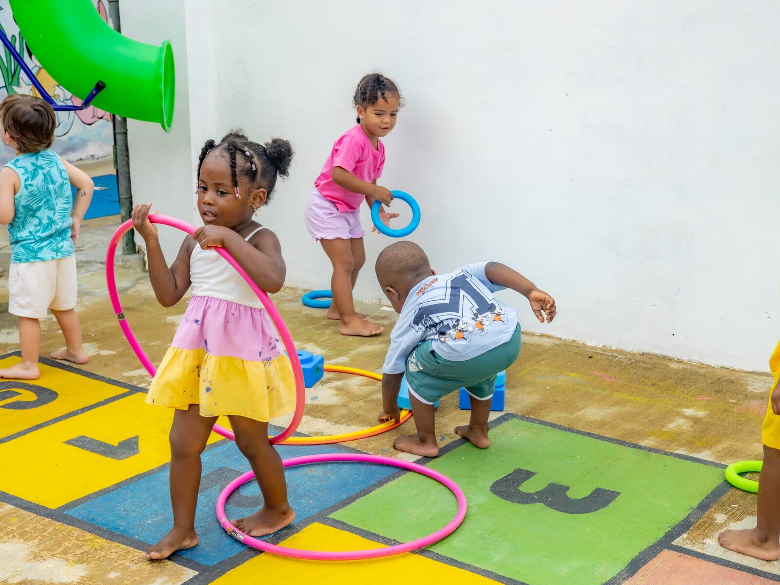 Children playing with hula hoops near the outdoor play equipment