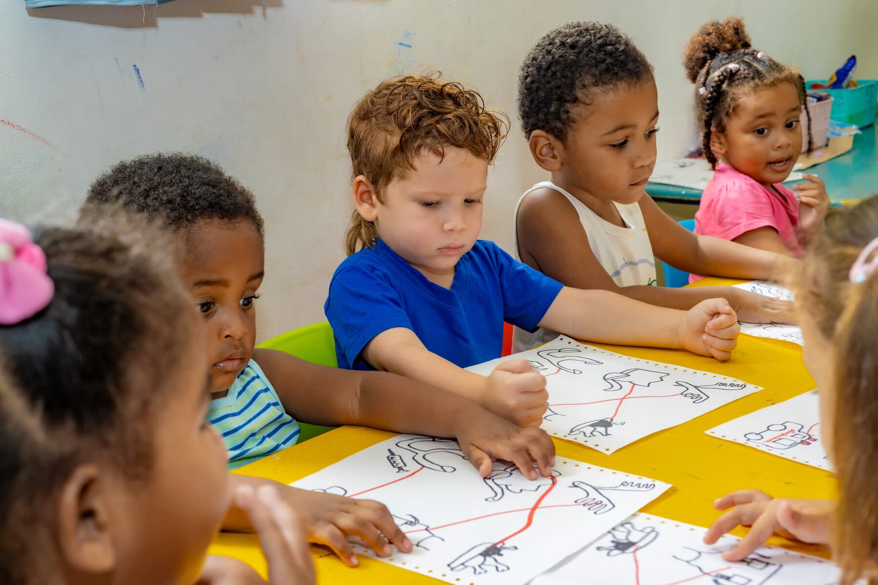 Preschool-age children engaged together at a colourful sensory activity table